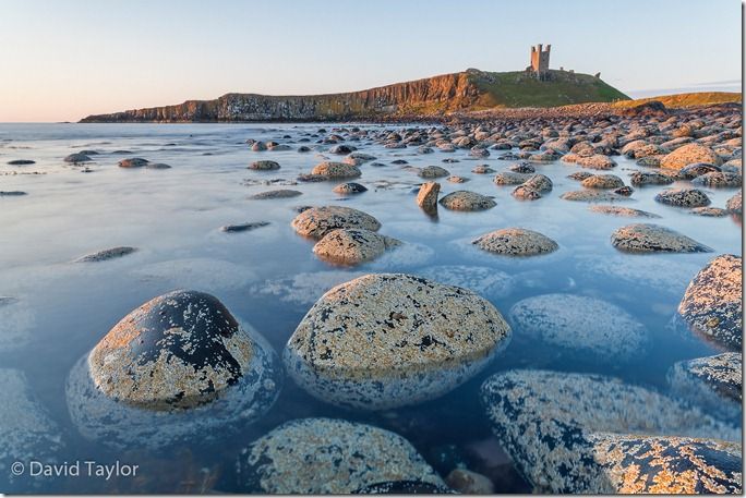 The view of Dunstanburgh Castle from the north bay showing the Lilburn Tower and Greymare rocks, Northumberland, England