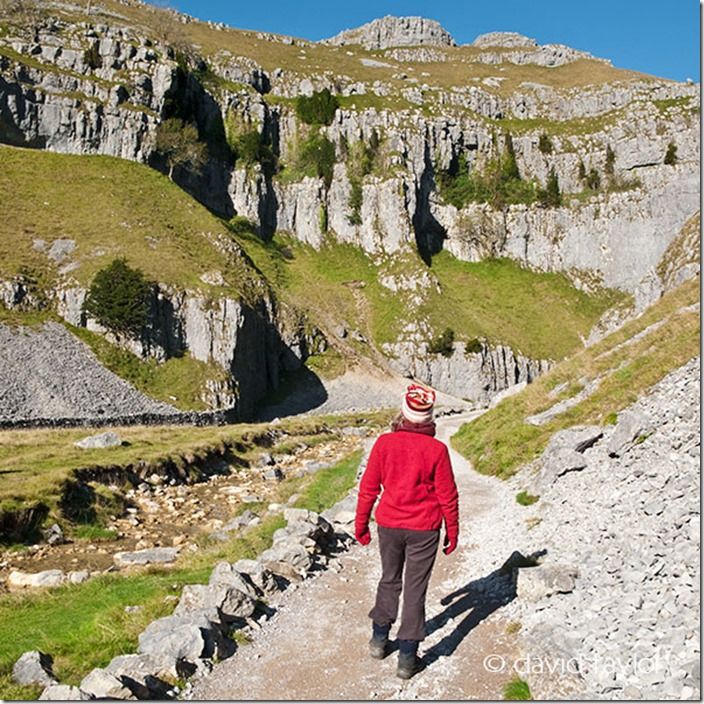 Young woman in walking clothes looking down Gordale Scar in the Malhamdale district of the Yorkshire Dales National Park, England