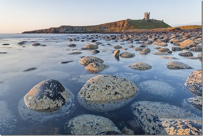 The view of Dunstanburgh Castle from the north bay showing the Lilburn Tower and Greymare rocks, Northumberland, England