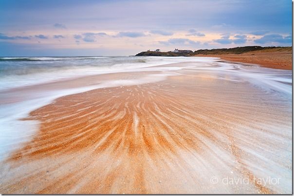 Waves washing over the sandy beach near Seaton Sluice on the south Northumberland coast, England